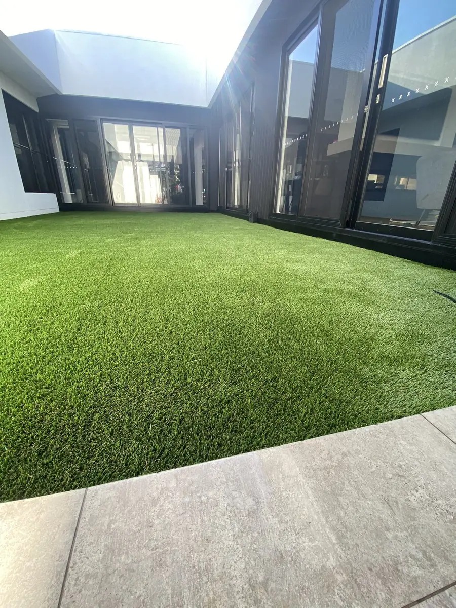 Courtyard turfed over concrete with glass doors